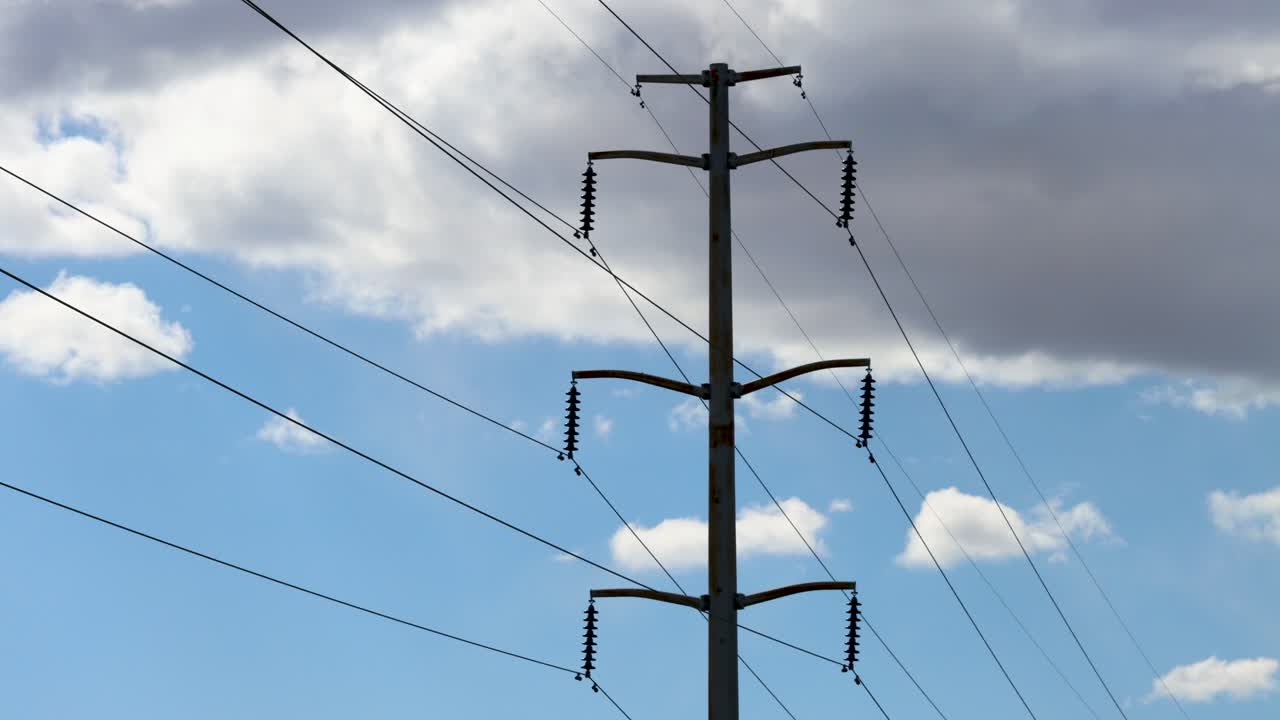 A windy day time lapse of a High Voltage Power line and clouds forming and passing behind it as is shakes and shimmies in the wind
