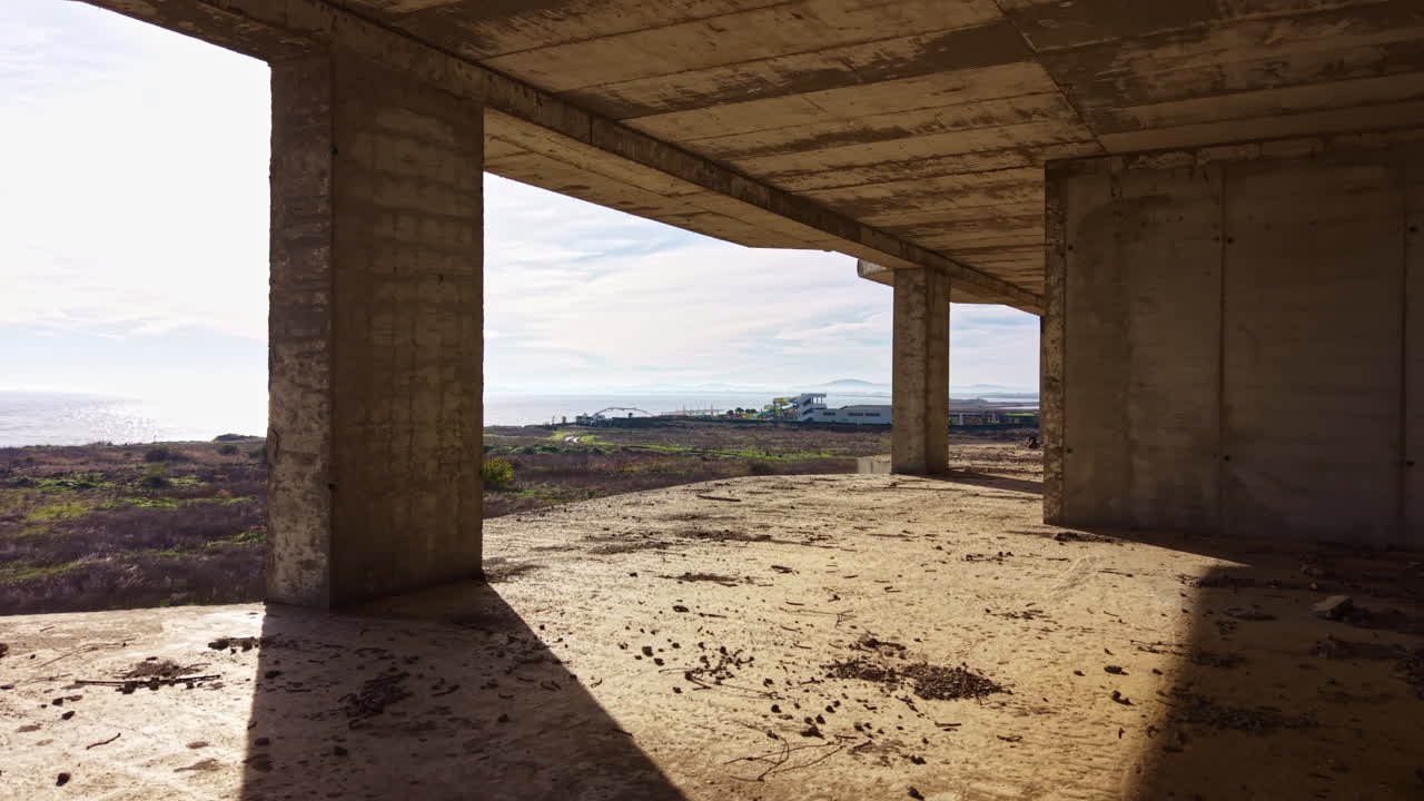 Ombre e riflessi giocano in una struttura abbandonata che si affaccia su un vasto paesaggio durante una mattinata tranquilla