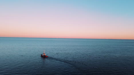 drone flying over the fishing boat sailing on the sea at the sunset