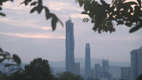 Kuala-Lumpur’s-Dawn-City-View-on-Malaysia-Tallest-Buildings,-Warisan-Merdeka-Tower-and-The-Exchange-106-from-forest-panning-from-right-to-left