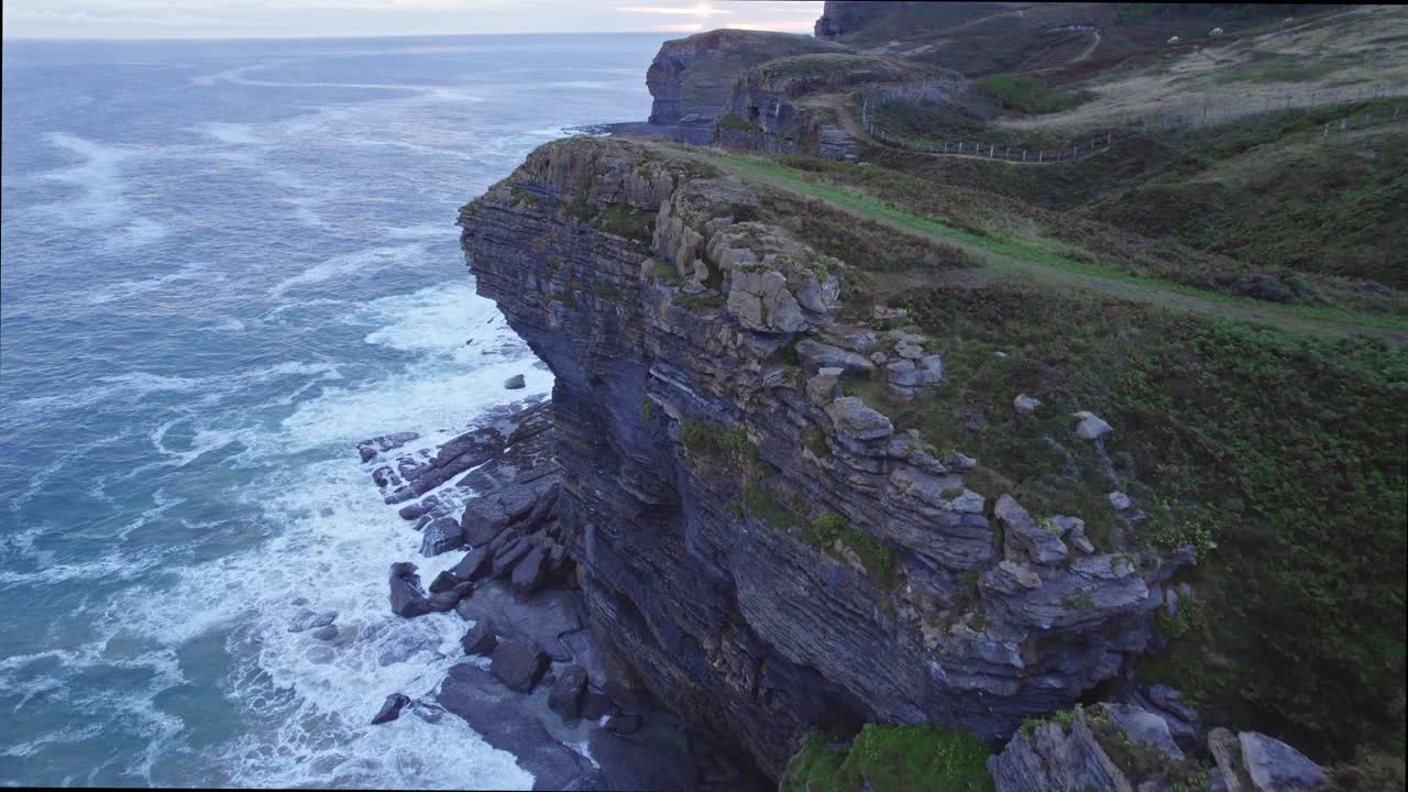 Drone capture the edge of island of Isla in Cantabria overlooking the blue sea on a cloudy day