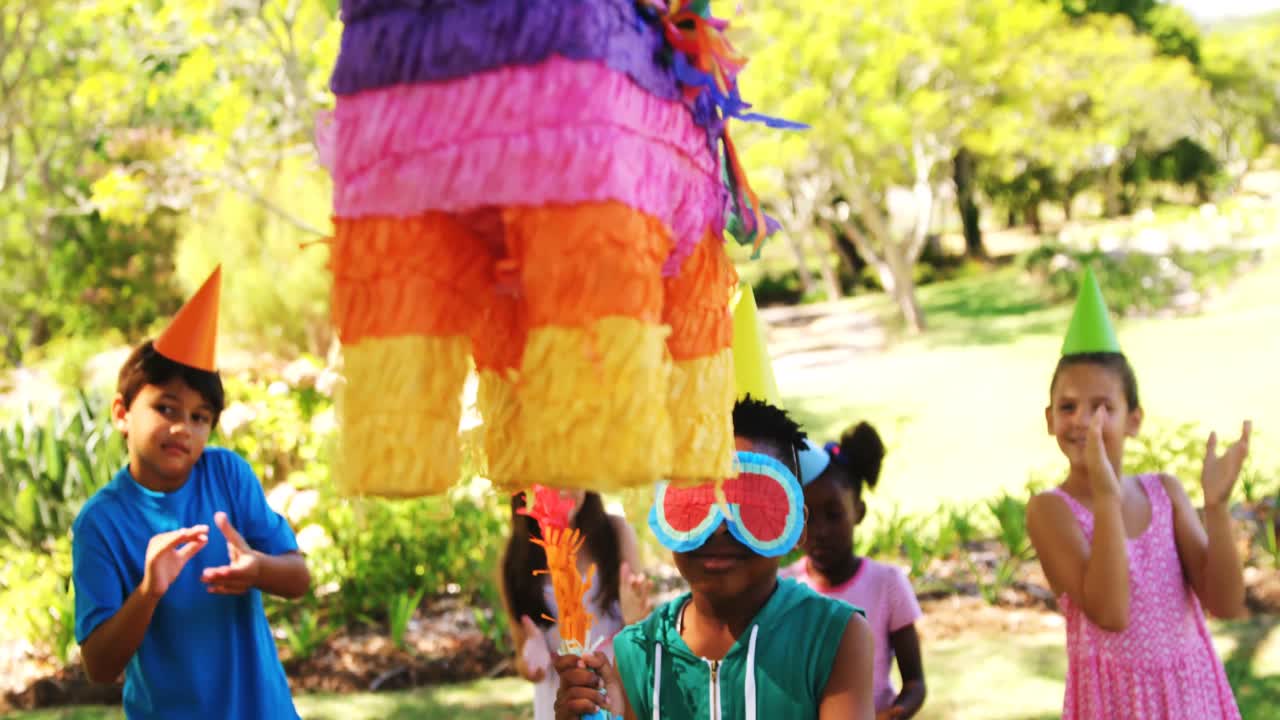 Boy holding multicolored puppet while celebrating birthday with friends