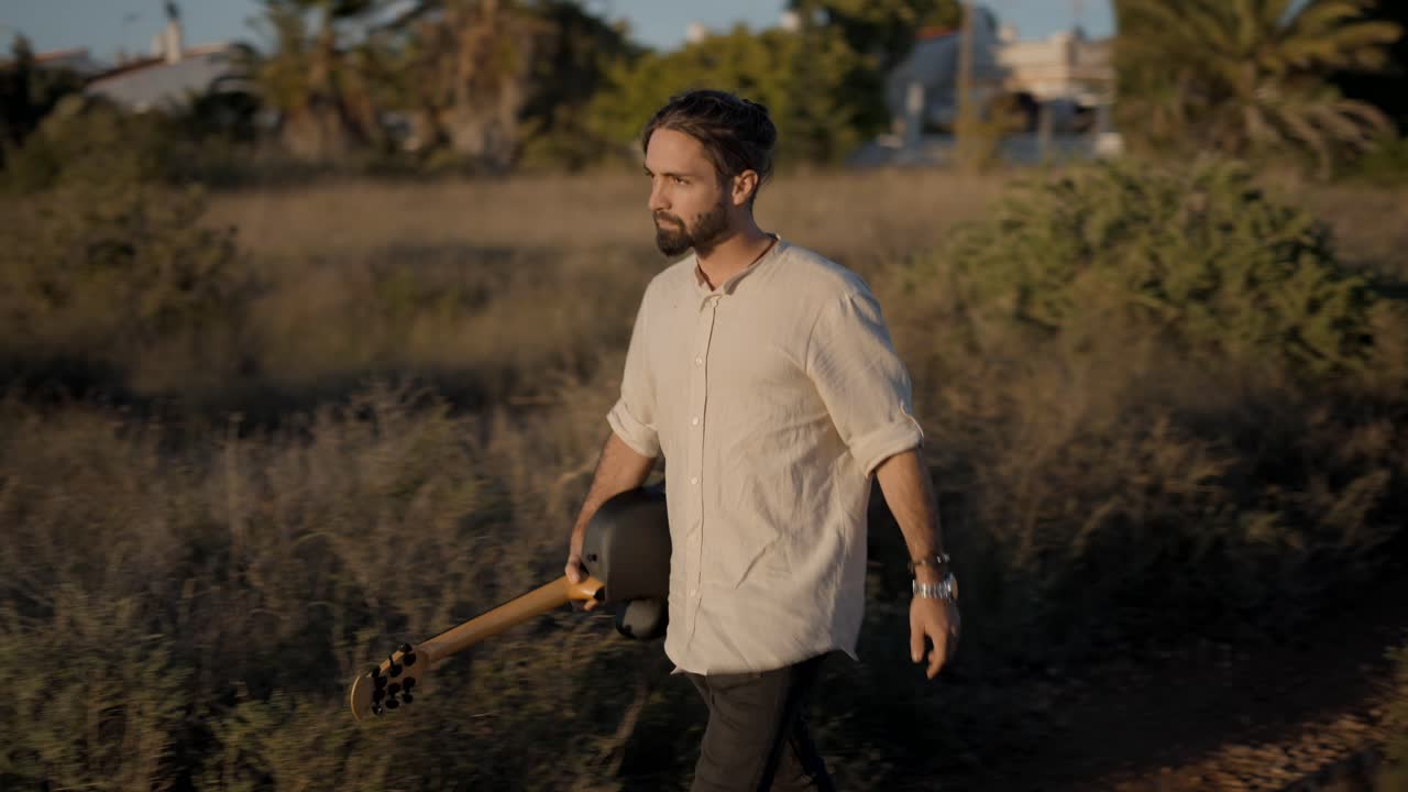 Man with Guitar in a Countryside Field at Sunset