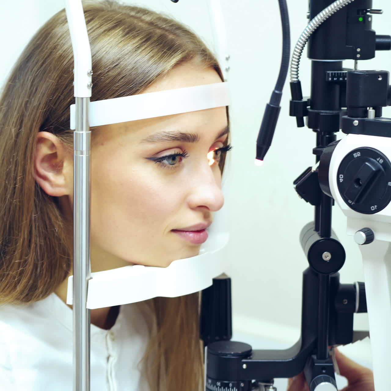 Young woman checking her eyes in clinic. Biomicroscopy device. Doctor examining eye structure of a female patient with the help of modern medical equipment. Professional health care.