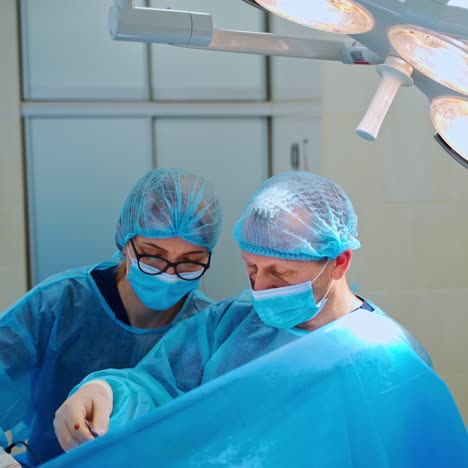 surgeon and a nurse doing an operation in clinic. professional doctor and assistant in medical uniform perform a surgery in the modern operating center.