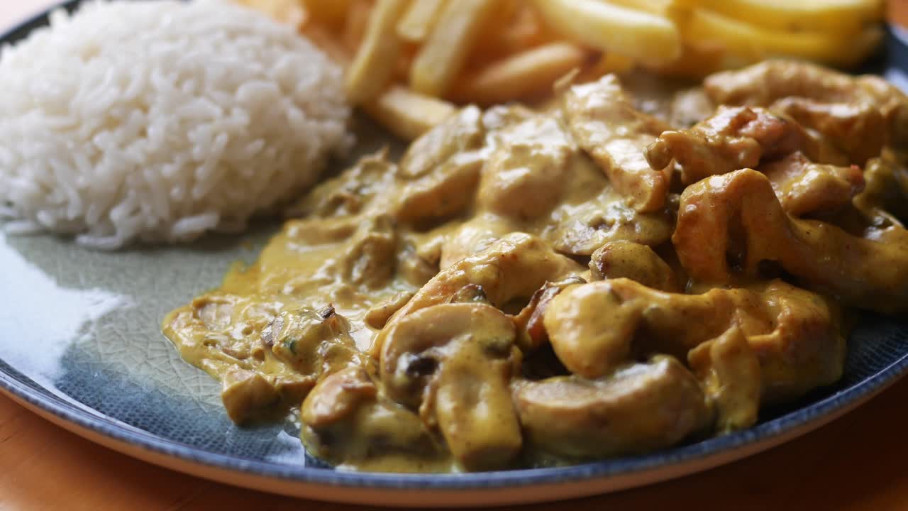 delicioso pollo con setas y salsa cremosa, servido con arroz y papas fritas