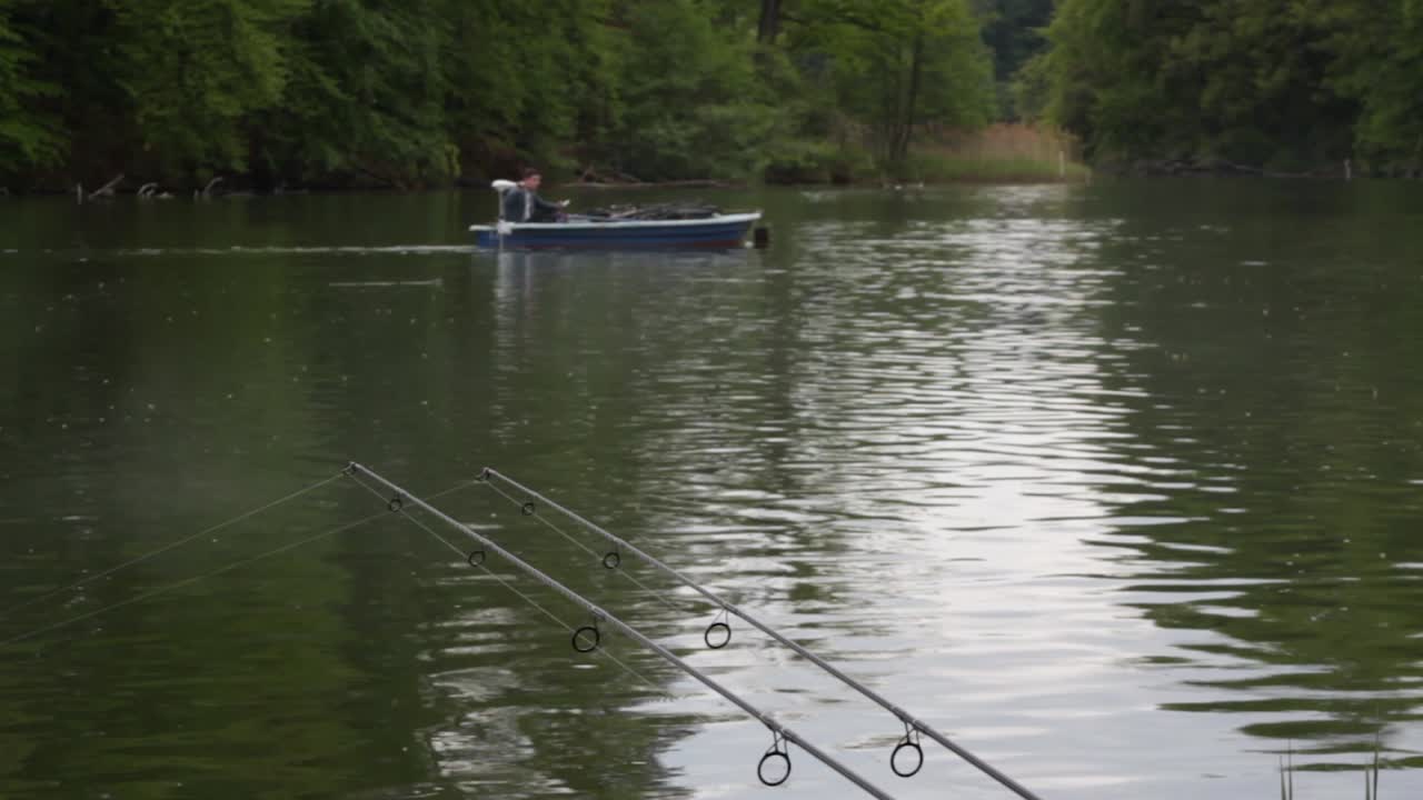 Fishing rod´s on the lakeside with a fisherboat in the backround
