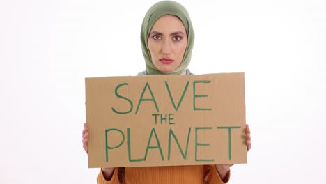 young woman in hijab holds "save the planet" sign against white background