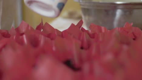 close-up of a pastry chef pouring batter into cupcake liners for baking