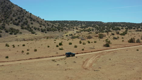 aerial following vehicle through desert landscape on remote dirt road