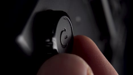 hand rotates the power control button of a black plastic lighting device