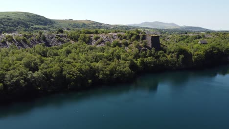 Vista-Aérea-Del-Valle-Del-Bosque-Galés-Eje-Minero-De-Pizarra-Y-Lago-De-Cantera-Panorámica-A-Través-De-Las-Montañas-De-Snowdonia