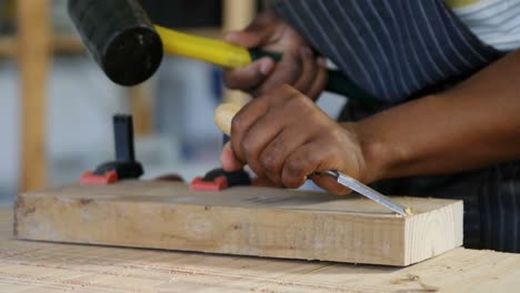 Mid section of carpenter carving wood with hammer at table 4k