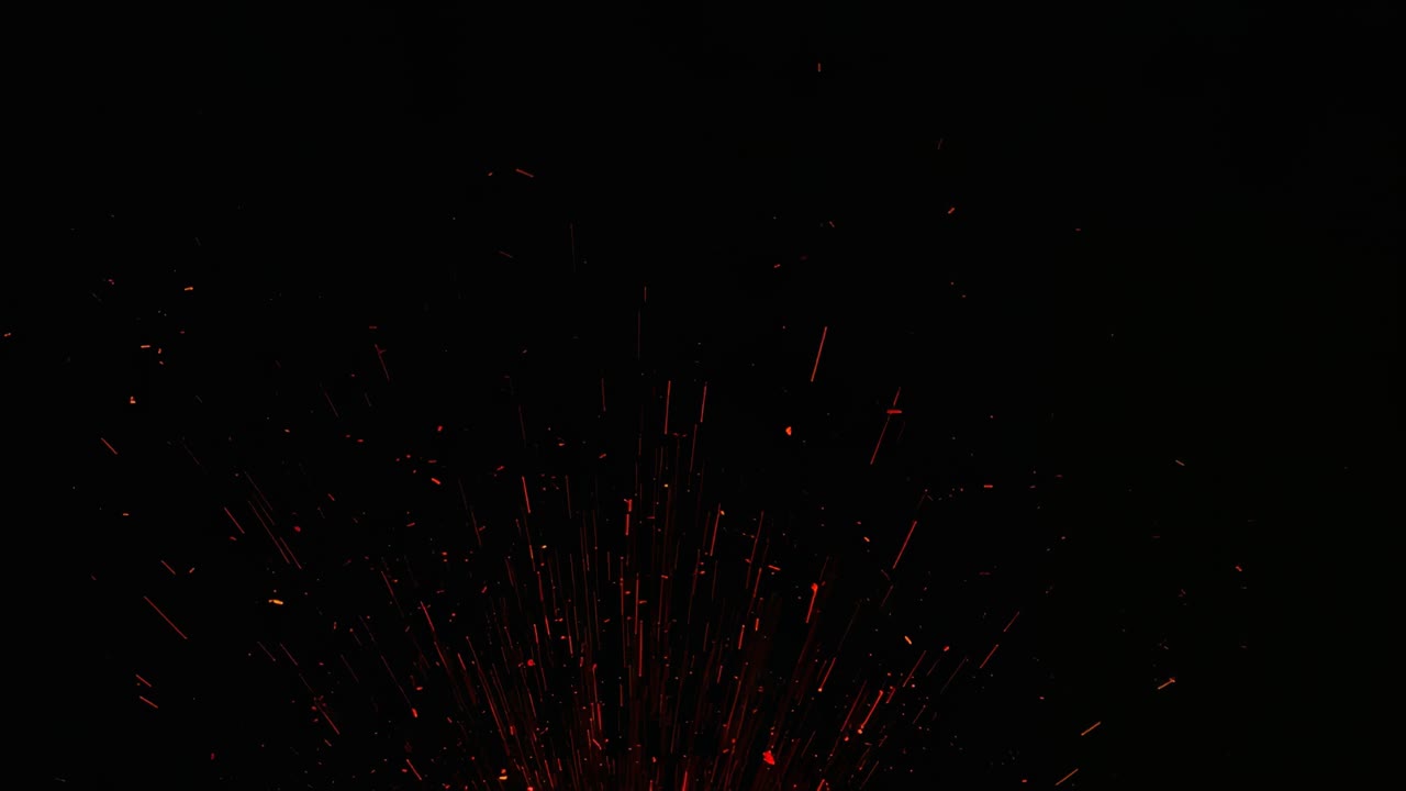 Bursting red-orange plume rising from bright core against dark backdrop, emitting long ember trails