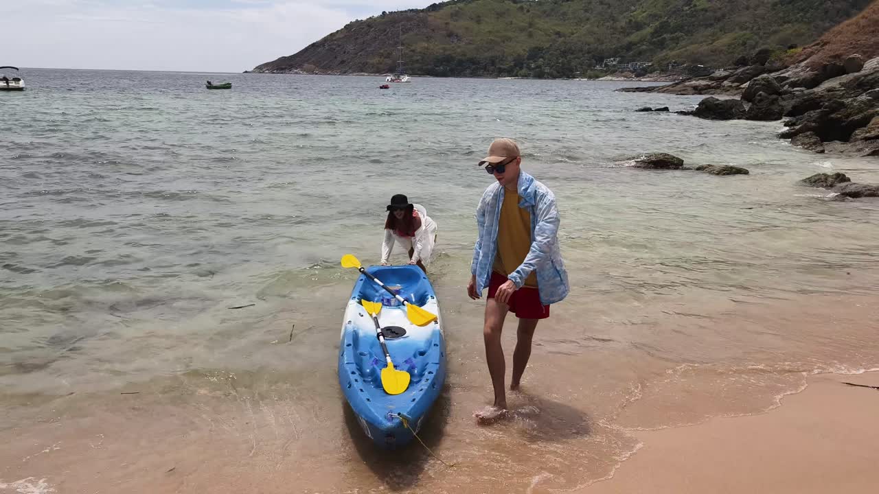 Couple loading a kayak on a beautiful beach