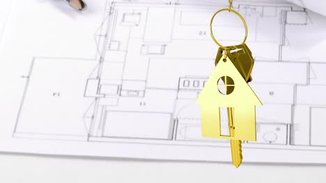 Hausschlüssel-Und-Schlüsselanhänger-Hängen-Mit-Haus-Im-Hintergrund