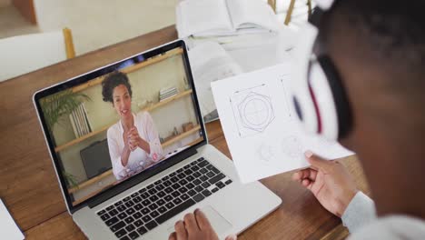 Estudiante-Universitario-Afroamericano-Sosteniendo-Notas-Mientras-Realiza-Una-Videollamada-En-Una-Computadora-Portátil-En-Casa