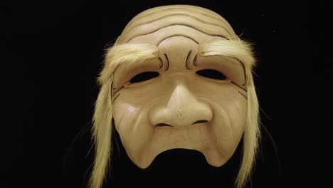 balinese traditional mask of an old men, bali indonesia wooden cultural art, black infinite background, closeup