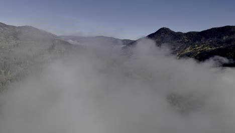 vista da montanha revelada: drone voa acima das nuvens para revelar picos arborizados