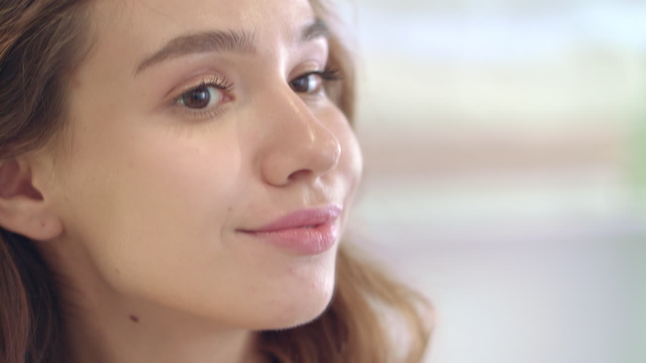 mujer joven con cabello rizado y rostro de maquillaje perfecto posando frente al espejo del baño
