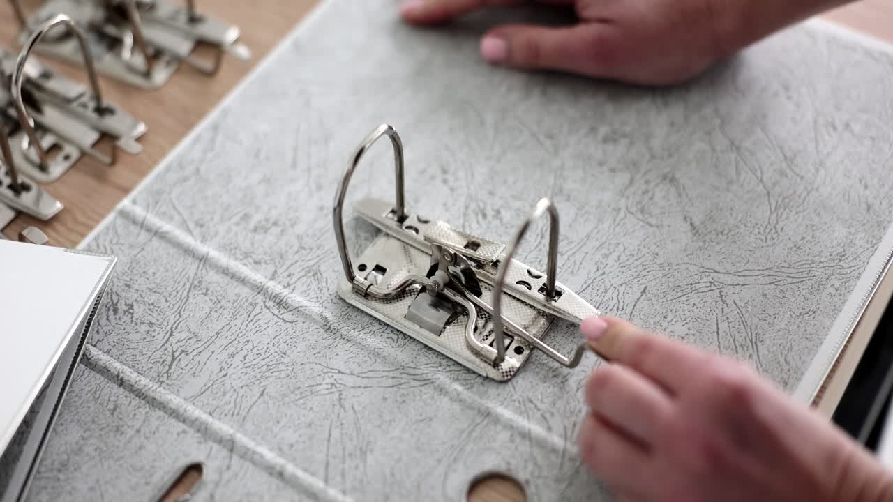 Close-up of hands assembling ring binder mechanism