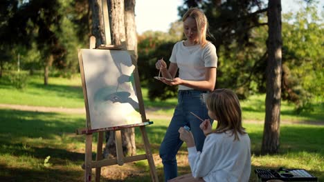 two girls painting outdoors in a park