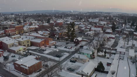aerial establishing shot of small town in usa, covered in snow at sunset, sunrise
