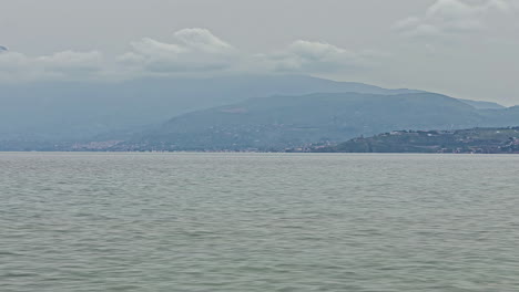 Toma-Estática-De-Lapso-De-Tiempo-Del-Hermoso-Mar-Tranquilo-Frente-A-La-Costa-Italiana-De-Sicilia-En-Italia-Con-Vistas-A-Las-Nubes-Que-Pasan-Y-Las-Montañas-Al-Fondo