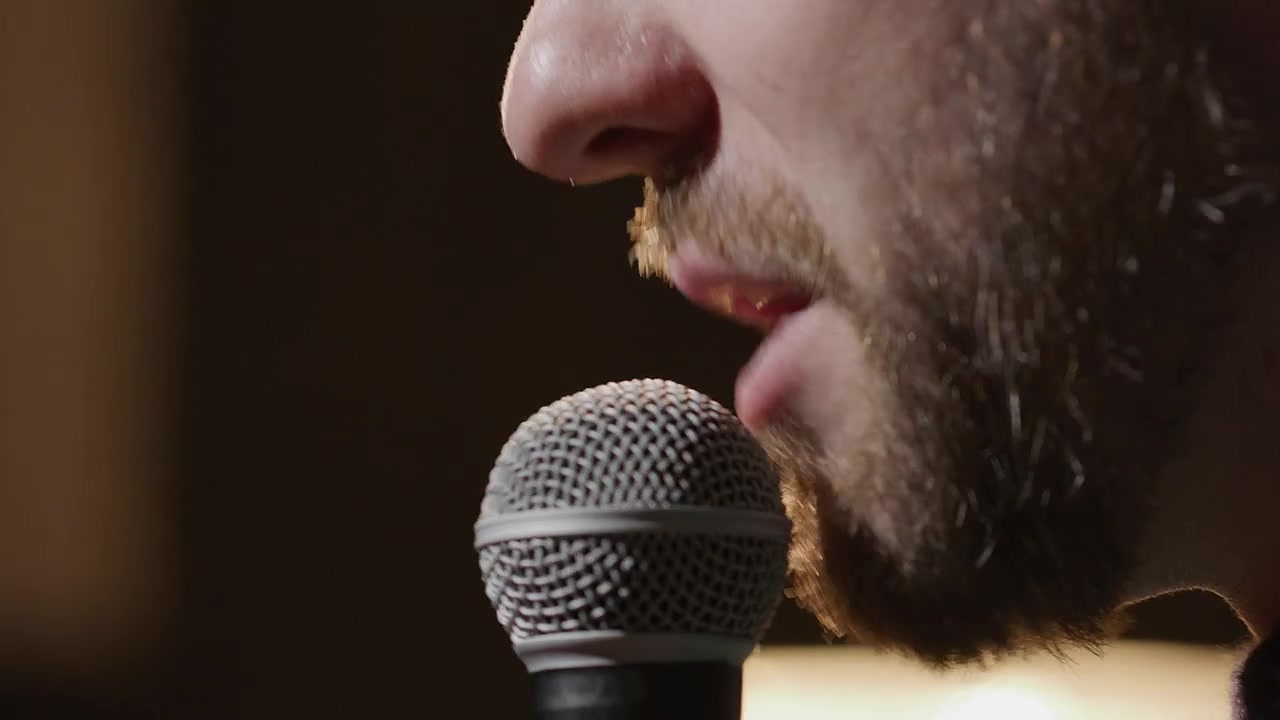 Primissimo piano di un uomo che parla al microfono sul palco.