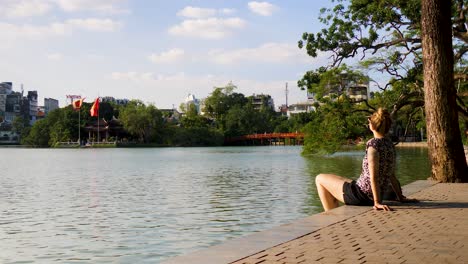 cityscape of hanoi in the background a young woman relaxes at hoan kiem lake