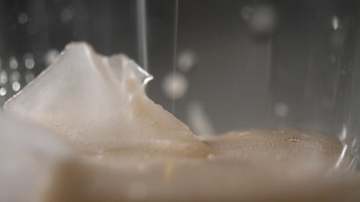 Cola being poured over ice in macro