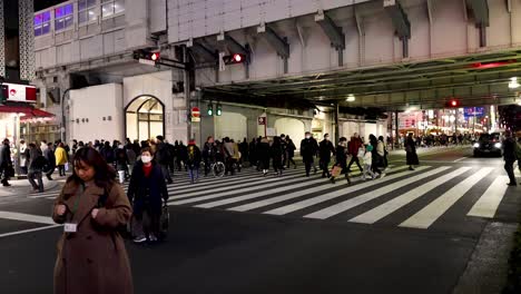 pedestrians crossing busy urban street after dark