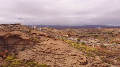 Paisaje-De-Aspecto-Desértico-De-La-Isla-De-Tenerife-Con-Carretera-Y-Molinos-De-Viento,-Antena