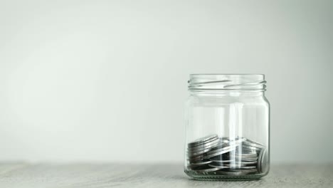 close up money coin falling into glass jar , a money saving , donation or business financial growth concept , 4k dci resolution , vintage retro color tone