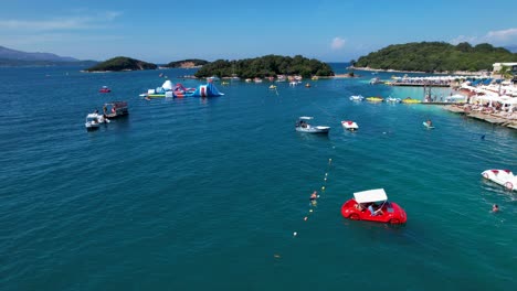 Paraíso-Costero-De-Ksamil:-Barcos-Turísticos-En-Mares-Esmeralda,-Playas-De-Arena-Blanca,-Sombrillas-Y-Destinos-Turísticos-Para-Unas-Idílicas-Vacaciones-De-Verano.