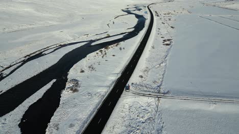 road by river in snowy iceland landscape - aerial drone flight