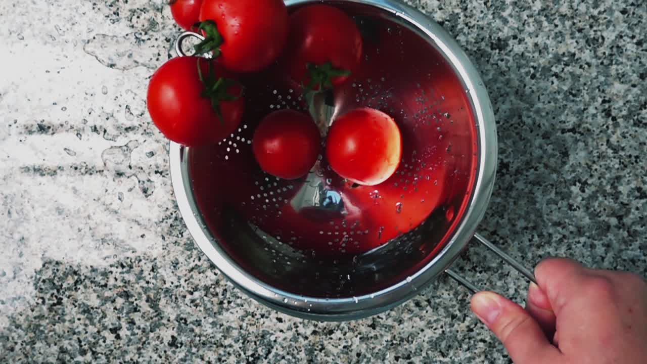 Mescolamento di pomodori in uno scolapasta. Sgocciolamento dei pomodori dall'acqua. Slow motion