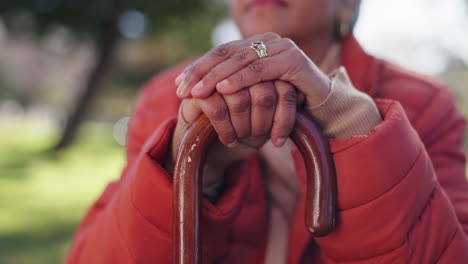 senior woman holding a walking stick in a park