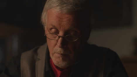 old passionate man writes a letter in his office at night
