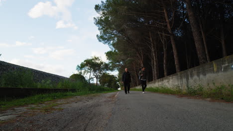 elderly father and son walking on a path near the woods