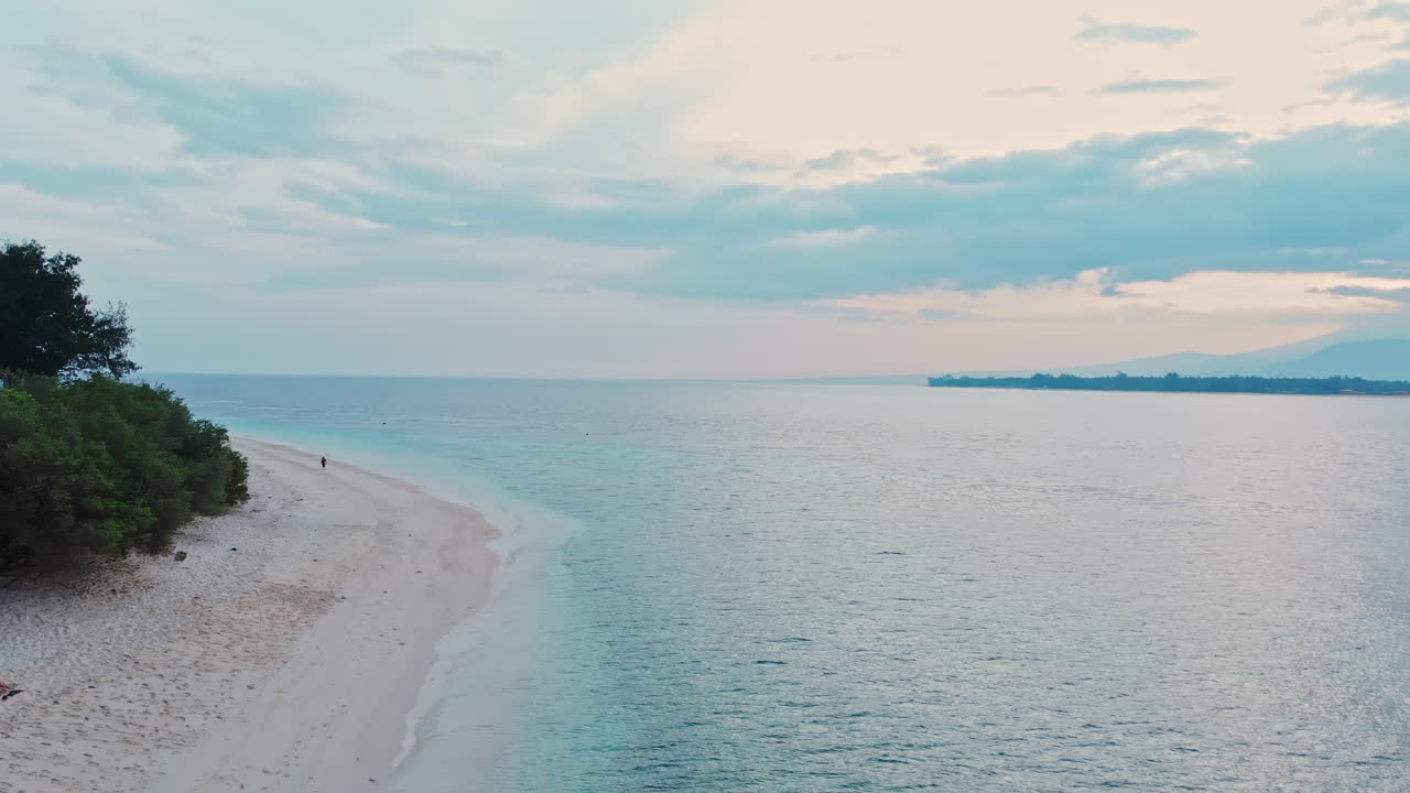 공중 - 드론은 인도네시아 발리에서 일출 전 이른 아침 열대 낙원 해변의 탁 트인 전망을 보여주기 위해 수위에서 상승합니다.