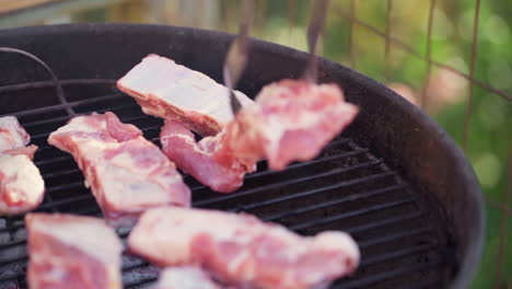 slow motion of tongs laying meat on smokey bbq grill