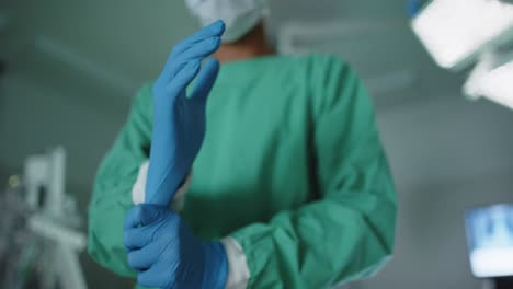 asian male surgeon wearing medical gloves in operating room in slow motion