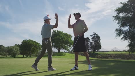 caucasian male golfers reaching down a ball out of the hole on a golf course on a sunny day