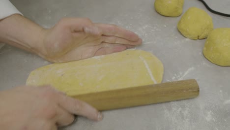 Rolling-out-pasta-dough-on-kitchen-cooking-table