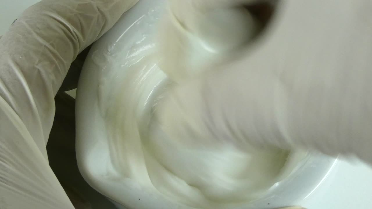 약국 실험실에서 장갑을 쓴 손이 도자기 모터에 두꺼운  향을 는 거대한 광경입니다.