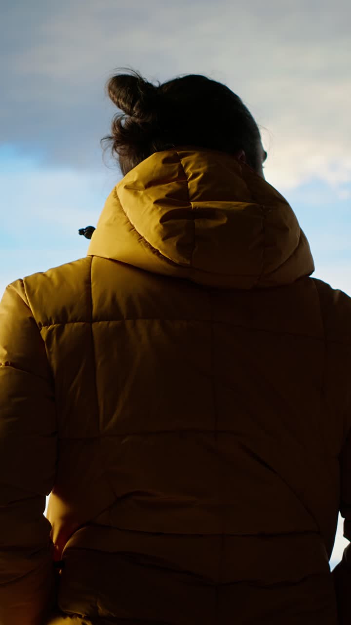 Uomo pensieroso con piumino giallo che osserva il panorama montano.