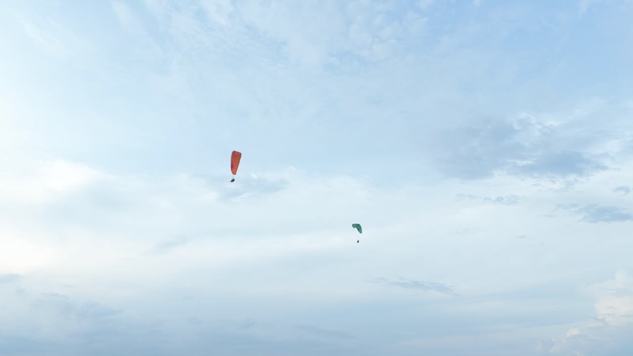 Due parapendisti che planano in alto sopra un paesaggio costiero panoramico.