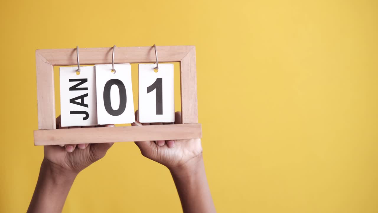 manos sosteniendo un calendario de madera que muestra el 1 de enero