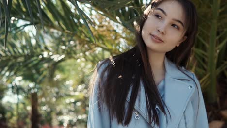 woman in a blue jacket in a palm tree grove